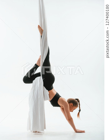 Professional occupation. Young beautiful woman doing fly yoga against white background Professional occupation. Young beautiful woman doing fly yoga against white background 127400180