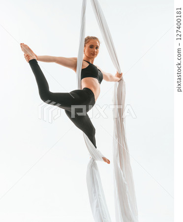 Professional occupation. Young beautiful woman doing fly yoga against white background Professional occupation. Young beautiful woman doing fly yoga against white background 127400181