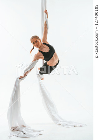 Professional occupation. Young beautiful woman doing fly yoga against white background Professional occupation. Young beautiful woman doing fly yoga against white background 127400185