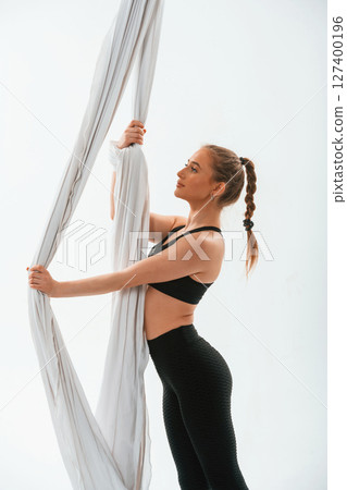 Holds the canvas. Young beautiful woman doing fly yoga against white background 127400196