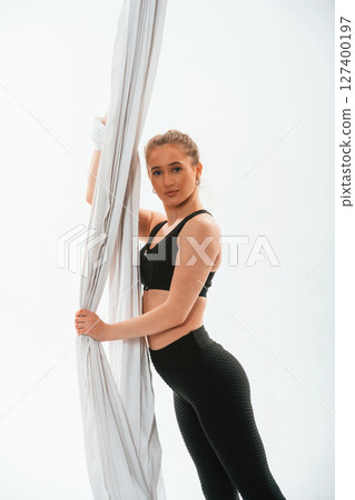 Holds the canvas. Young beautiful woman doing fly yoga against white background Holds the canvas. Young beautiful woman doing fly yoga against white background 127400197