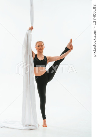 Holds the canvas. Young beautiful woman doing fly yoga against white background Holds the canvas. Young beautiful woman doing fly yoga against white background 127400198