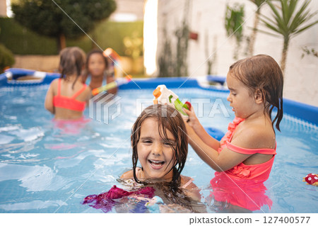 Children playing joyfully in a backyard pool on a sunny day 127400577