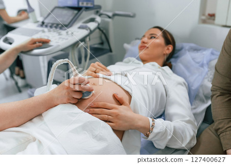 Pregnant woman is lying down in the hospital, doctor does ultrasound Pregnant woman is lying down in the hospital, doctor does ultrasound 127400627