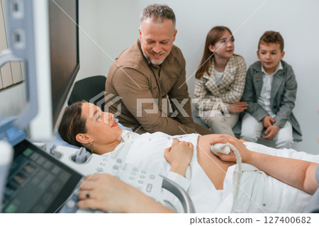 Man and kids. Pregnant woman is lying down in the hospital, doctor does ultrasound 127400682