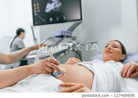 Smiling, medical procedure. Pregnant woman is lying down in the hospital, doctor does ultrasound Smiling, medical procedure. Pregnant woman is lying down in the hospital, doctor does ultrasound 127400696