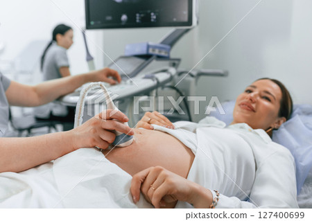 Smiling, medical procedure. Pregnant woman is lying down in the hospital, doctor does ultrasound Smiling, medical procedure. Pregnant woman is lying down in the hospital, doctor does ultrasound 127400699