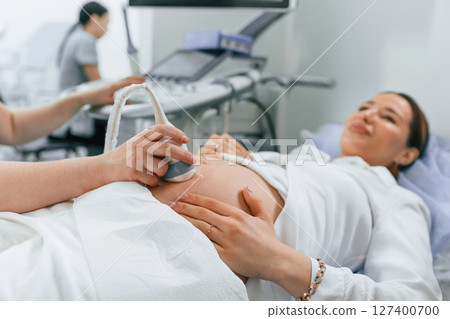 Pregnant woman is lying down in the hospital, doctor does ultrasound 127400700