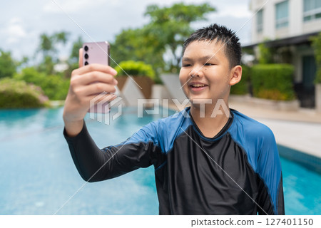 Asian teenage boy using phone after swimming in pool Asian teenage boy using phone after swimming in pool 127401150