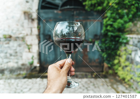 Red Wine Glass in Hand with Stone Cellar Background in France or Italy Red Wine Glass in Hand with Stone Cellar Background in France or Italy 127401587