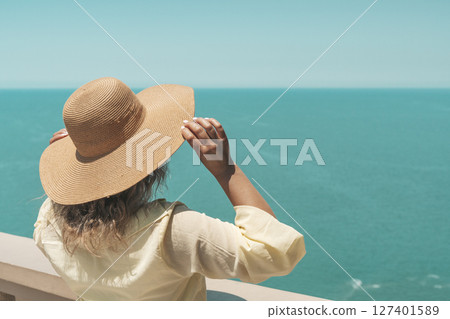 Woman in Summer Hat Looking at Sea Horizon from Cliff 127401589