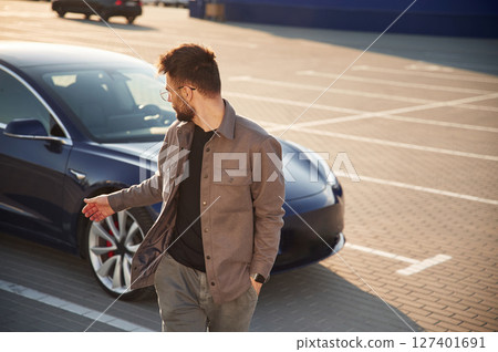 Front view. Man is standing near his electric car outdoors 127401691