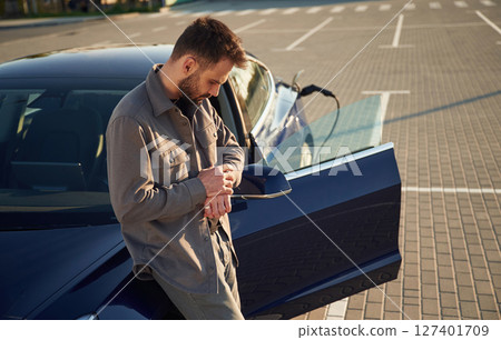 Charging the automobile. Man is standing near his electric car outdoors 127401709