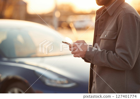 Man is standing near his electric car outdoors 127401774