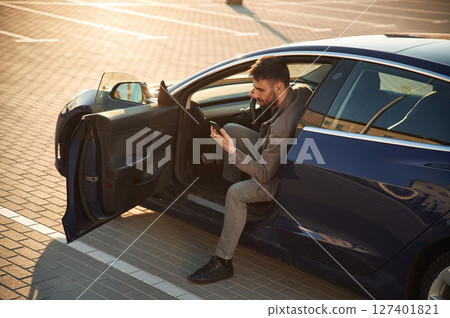 Sitting on the seat. Man is in his electric car outdoors 127401821