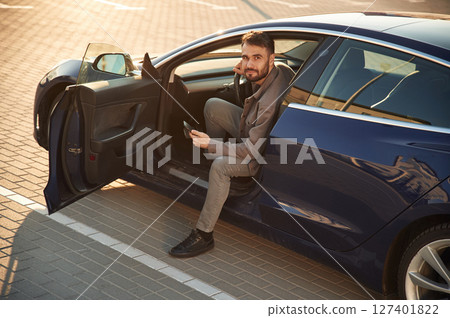 Sitting on the seat. Man is in his electric car outdoors Sitting on the seat. Man is in his electric car outdoors 127401822
