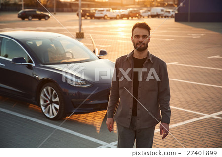 Handsome man is standing near his electric car outdoors 127401899