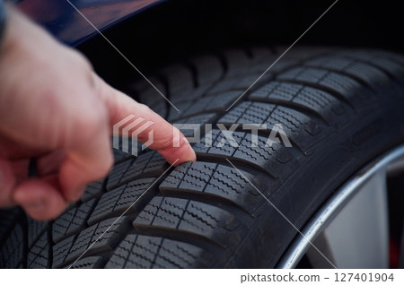 Close up view of man's hand that touching the automobile tire 127401904
