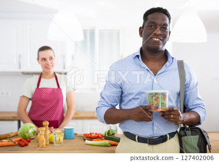 Man holding container with vegetable salad prepared by caring wife 127402006