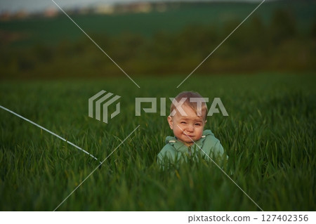 Cute little baby boy is in the agricultural field at daytime Cute little baby boy is in the agricultural field at daytime 127402356