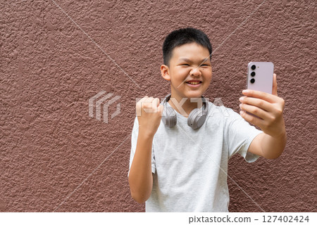 Teenager Boy Portrait Against Plain Wall in Natural Light 127402424