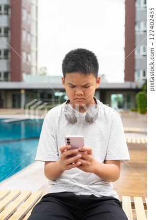 Teenage Boy at Poolside During Summer Using Phone Teenage Boy at Poolside During Summer Using Phone 127402435
