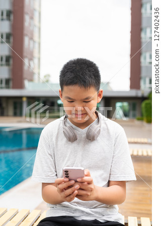 Teenage Boy at Poolside During Summer Using Phone Teenage Boy at Poolside During Summer Using Phone 127402436