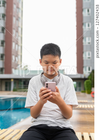 Teenage Boy at Poolside During Summer Using Phone 127402438
