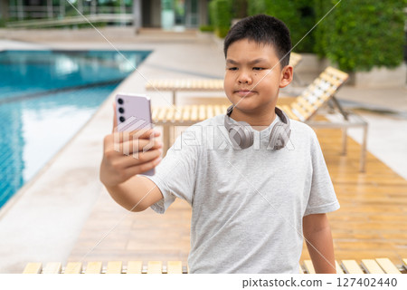 Teenage Boy at Poolside During Summer Using Phone 127402440