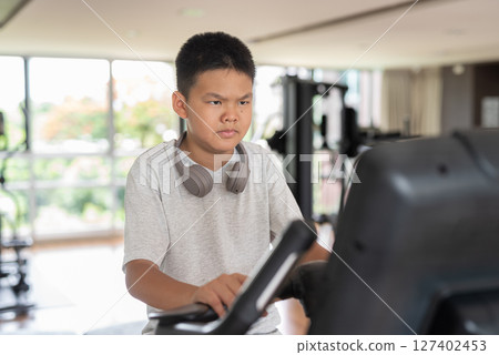 Young Teen Boy Working Out on Exercise Bike 127402453