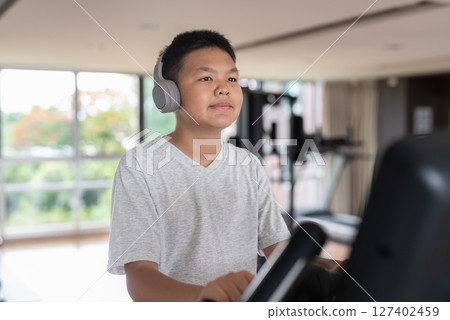 Young Teen Boy Working Out on Exercise Bike 127402459