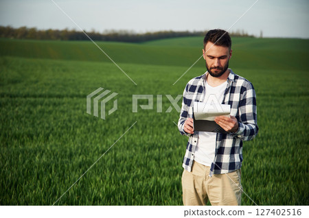 On agricultural field. Handsome young man 127402516