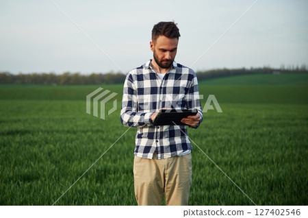 Spring season. Handsome young man is on agricultural field Spring season. Handsome young man is on agricultural field 127402546