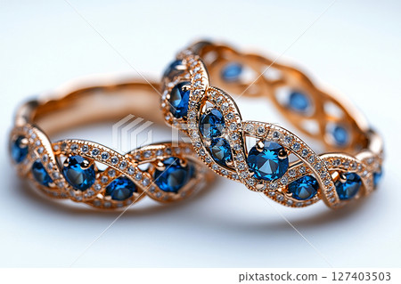 Luxurious pair of wedding rings with blue stones on a white background. Rococo-Renaissance style. 127403503