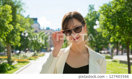 Smiling woman wearing sunglasses in a city park Smiling woman wearing sunglasses in a city park 127403566
