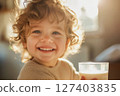 Smiling child in morning sun with glass of milk 127403835