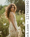 Bride in boho style dress walks through meadow field in summer day 127403840