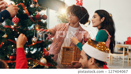 Christmas, ornament and tree with friends in living room of home for celebration or social event. December, decoration and party with group of happy people in apartment together for holiday season 127404067