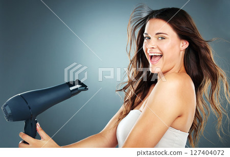 Woman, hair and hair dryer with smile in studio for self care, hair care or cosmetics by blue background. Girl, happy and excited with hairdryer for wellness, cosmetic care and beauty by backdrop Woman, hair and hair dryer with smile in studio for self care, hair care or cosmetics by blue background. Girl, happy and excited with hairdryer for wellness, cosmetic care and beauty by backdrop 127404072