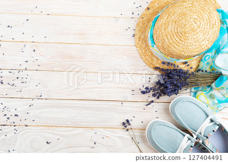 Straw hat, lavender flowers and  fabric moccasins on white planks vacation planning background flat lay with copy-space 127404491
