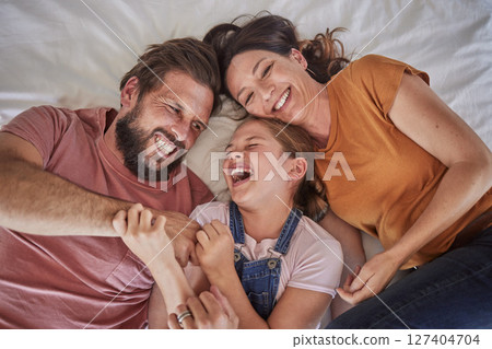 Family, bed and child with tickle, happy or comic play for quality time, bonding or home together. Above, parents and girl with happiness, laugh or crazy with love, mom and dad in happy family house 127404704
