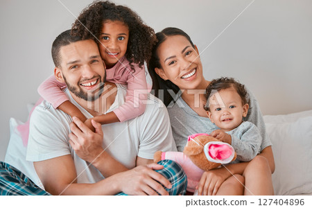 Bonding, care and smile from family in the bedroom with love, peace and relax together in the morning. Happy, affection and portrait of a mother and father with their girl children in bed for rest 127404896