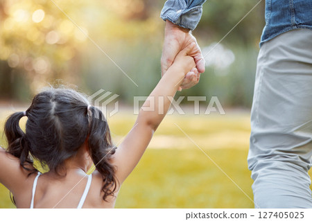 Holding hands, care and girl with father in a park with safety, support and security. Walk, trust and back of a child with dad in a backyard, field or nature in countryside for outdoor quality time Holding hands, care and girl with father in a park with safety, support and security. Walk, trust and back of a child with dad in a backyard, field or nature in countryside for outdoor quality time 127405025
