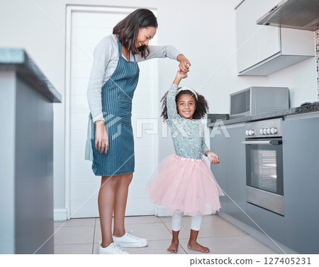 Mother, child and dancing in home kitchen for love, energy and fun together as a family with happiness, care and support. Black woman and girl or daughter with princess tutu to dance while cooking 127405231