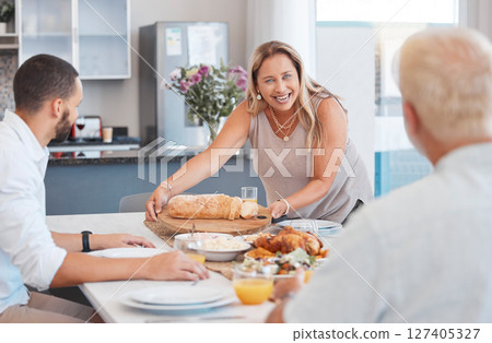 Lunch, celebration and happy family with food at a dining room table on holiday at the accommodation. Serving, dinner and senior woman with bread and chicken for hungry people in family home 127405327