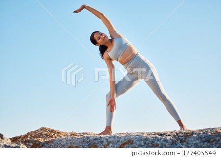 Fitness, health and yoga with a woman athlete stretching on a rock at the beach for mental health or wellness. Exercise, workout and training with a female yogi outdoor in nature for mindfulness 127405549