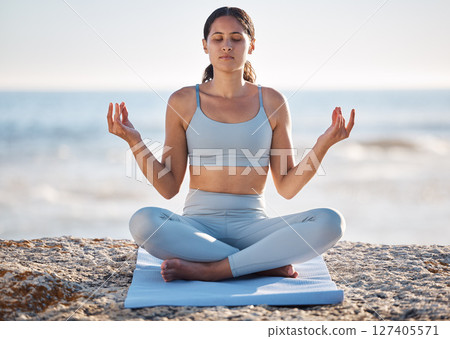 Calm, beach and woman doing meditation exercise for zen, health and wellness of the mind and body. Spiritual, fitness and healthy girl in lotus pose doing yoga or pilates workout by the ocean or sea. 127405571