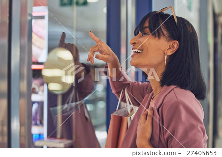 Happy woman, window and shopping, mall and excited to buy sales, discount products and luxury fashion clothes. Smile customer pointing in glass, shopping mall and choice, decision and retail boutique 127405653