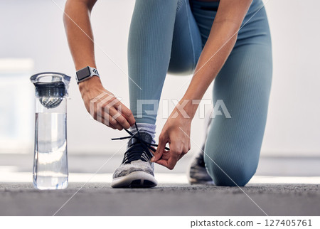 Fitness, woman and shoe for running preparation, workout or training exercise with water bottle in the outdoors. Female tying laces getting ready for sports exercising, run or healthy cardio outside 127405761