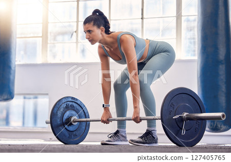 Fitness, woman and weightlifting barbell for workout, exercise or intense training at the gym. Active female exercising and lifting weights in sports for arm strength, legs or squats at a health club 127405765